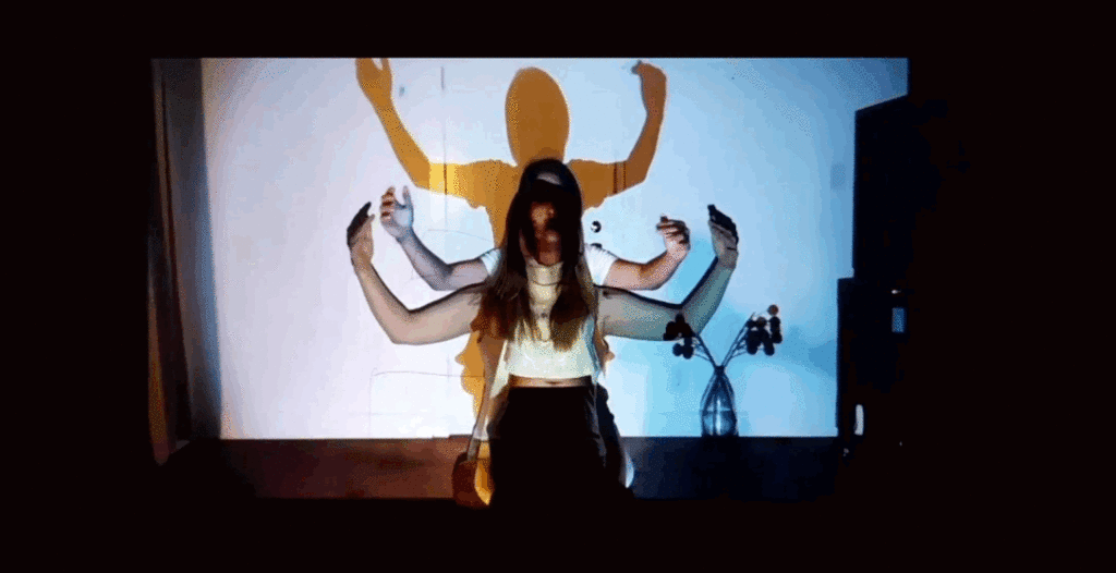 Video image of two woman superimposed on each other as if it were one woman with four arms.